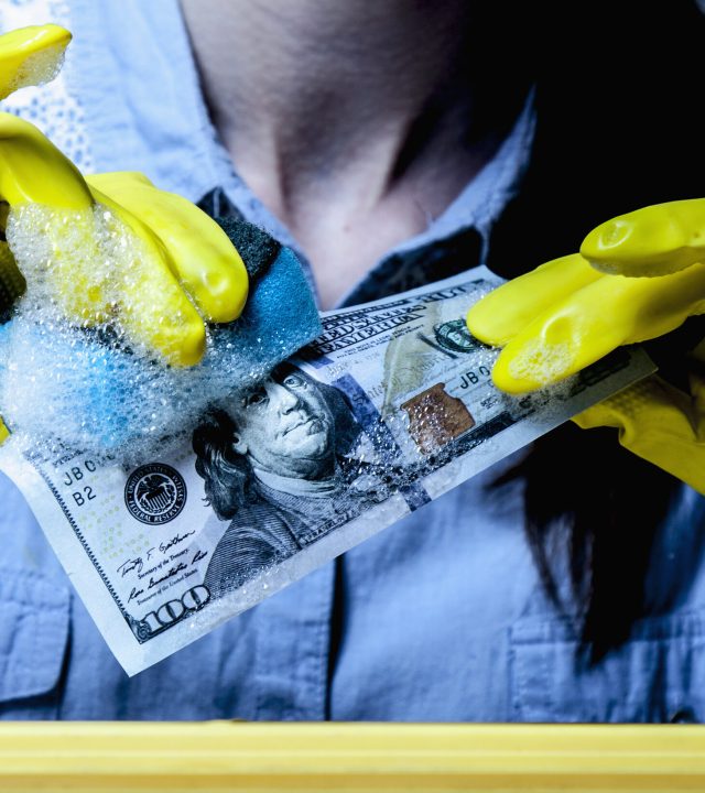 Beautiful young woman washes money as symbol of laundering and legalization of dollars. (Shadow money, bribe, bribery concept)